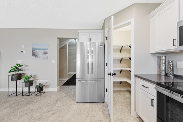 kitchen with white cabinetry, a textured ceiling, and appliances with stainless steel finishes