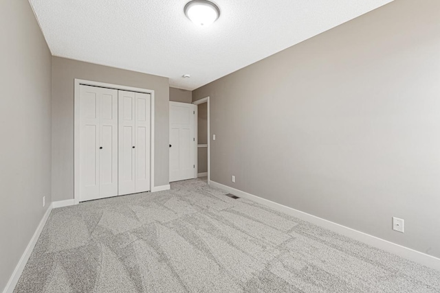 unfurnished bedroom with a closet, light colored carpet, and a textured ceiling