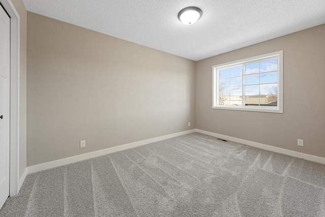 carpeted empty room with a textured ceiling