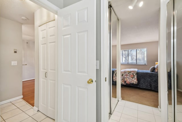 corridor featuring light tile patterned floors and a textured ceiling