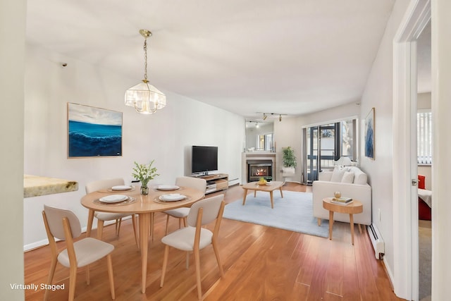 dining area featuring a chandelier, hardwood / wood-style floors, a baseboard radiator, and track lighting