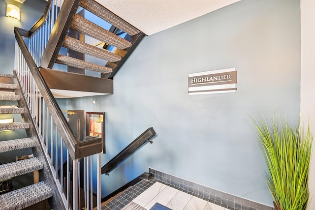 stairs with tile patterned floors and a textured ceiling