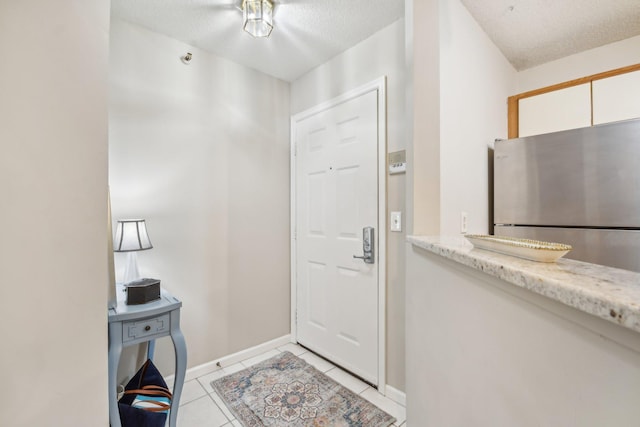 entryway featuring light tile patterned floors and a textured ceiling