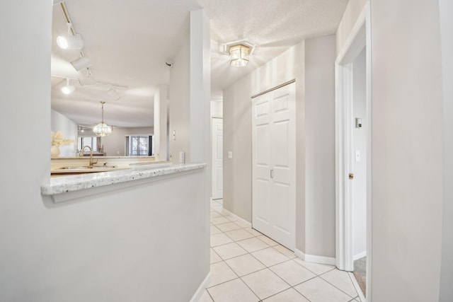 hallway with sink, light tile patterned floors, a chandelier, and a textured ceiling