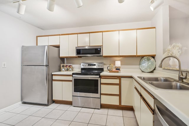 kitchen featuring light tile patterned flooring, appliances with stainless steel finishes, rail lighting, and sink