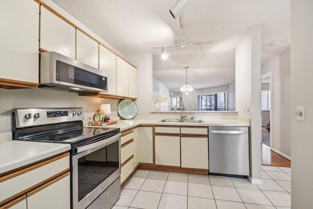 kitchen featuring rail lighting, stainless steel appliances, sink, white cabinetry, and light tile patterned flooring