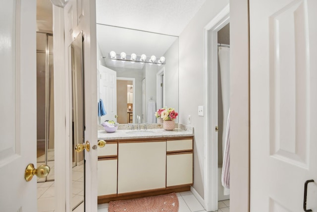 bathroom with a textured ceiling, vanity, and tile patterned floors