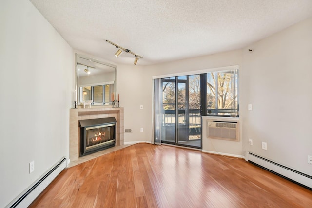 unfurnished living room with a textured ceiling, a wall mounted air conditioner, and baseboard heating