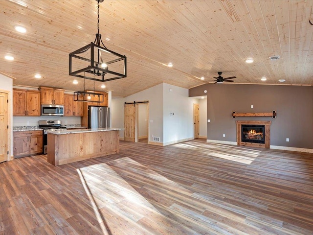 kitchen with pendant lighting, wooden ceiling, a barn door, and appliances with stainless steel finishes