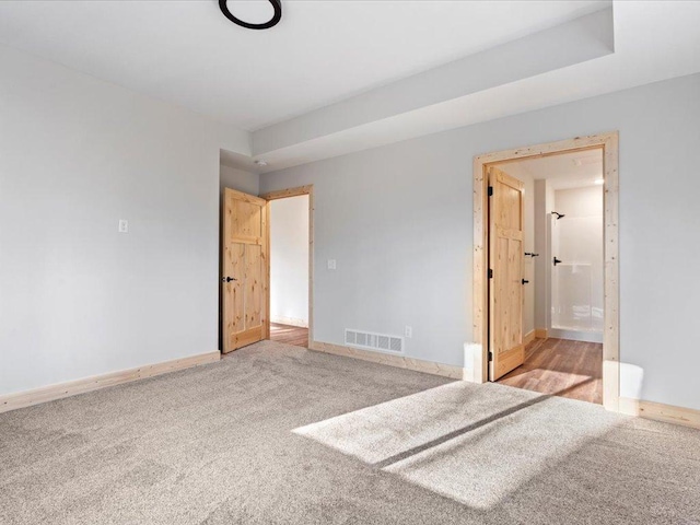 unfurnished bedroom featuring ensuite bath and light carpet