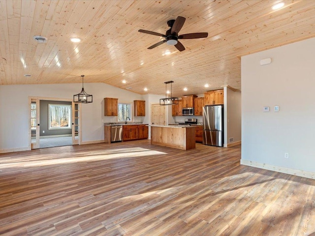 kitchen with hanging light fixtures, a kitchen island, appliances with stainless steel finishes, and lofted ceiling