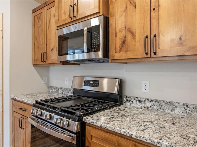 kitchen with light stone countertops, hardwood / wood-style flooring, and stainless steel appliances