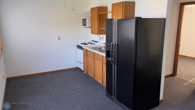 kitchen featuring dark colored carpet, white appliances, and sink