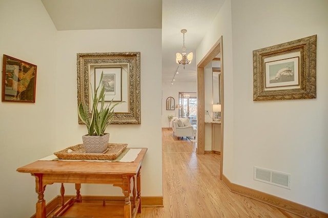 corridor with hardwood / wood-style flooring and an inviting chandelier