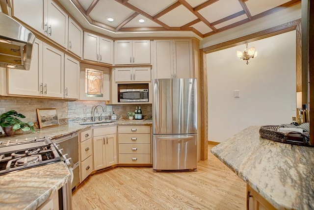 kitchen with appliances with stainless steel finishes, light stone counters, coffered ceiling, sink, and pendant lighting