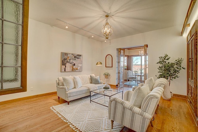 living room with french doors, light wood-type flooring, and an inviting chandelier