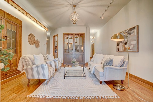 living room with rail lighting, a chandelier, and hardwood / wood-style flooring