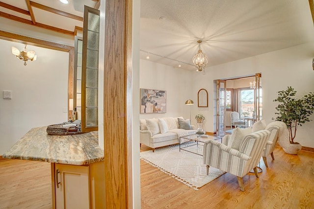 living room featuring a notable chandelier, light wood-type flooring, and french doors