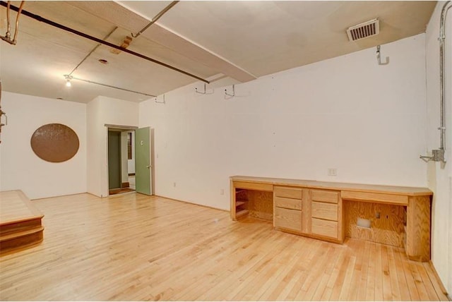 empty room with built in desk and wood-type flooring