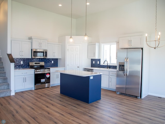 kitchen featuring white cabinets, stainless steel appliances, and a high ceiling