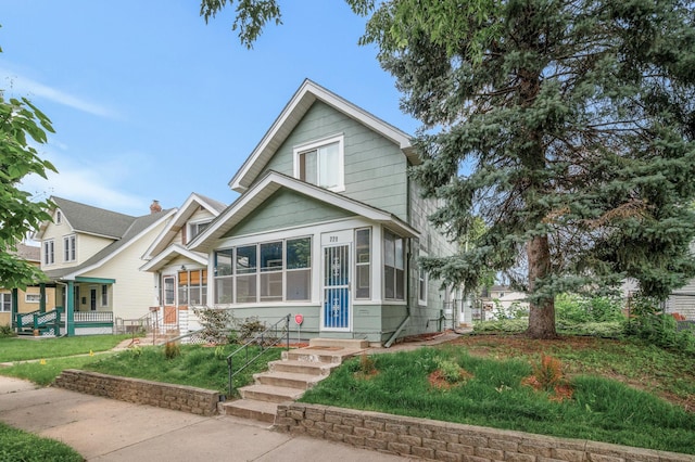 view of front of home featuring a sunroom and a front lawn