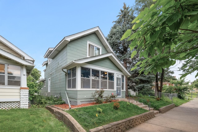 view of front of house featuring a sunroom and a front yard