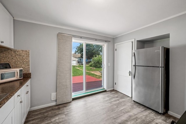 kitchen with backsplash, white cabinetry, stainless steel refrigerator, and light hardwood / wood-style floors