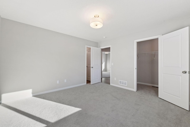 unfurnished bedroom featuring light colored carpet, a spacious closet, and a closet