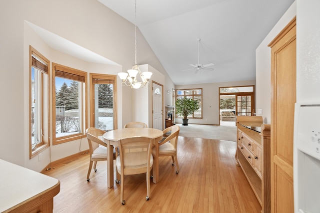 dining space featuring ceiling fan with notable chandelier, light hardwood / wood-style floors, lofted ceiling, and a healthy amount of sunlight