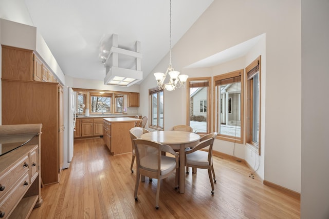 dining area with light hardwood / wood-style flooring, an inviting chandelier, and vaulted ceiling