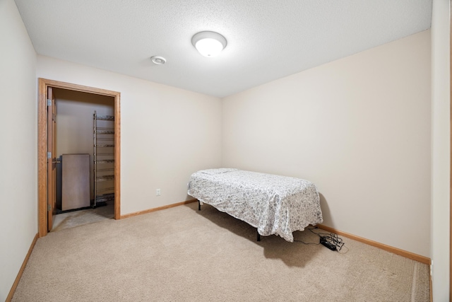 bedroom featuring a walk in closet, a textured ceiling, a closet, and carpet