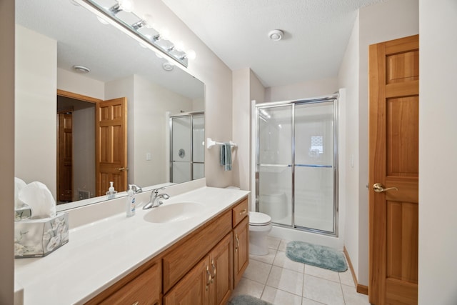 bathroom with toilet, a textured ceiling, tile patterned flooring, a shower with door, and vanity