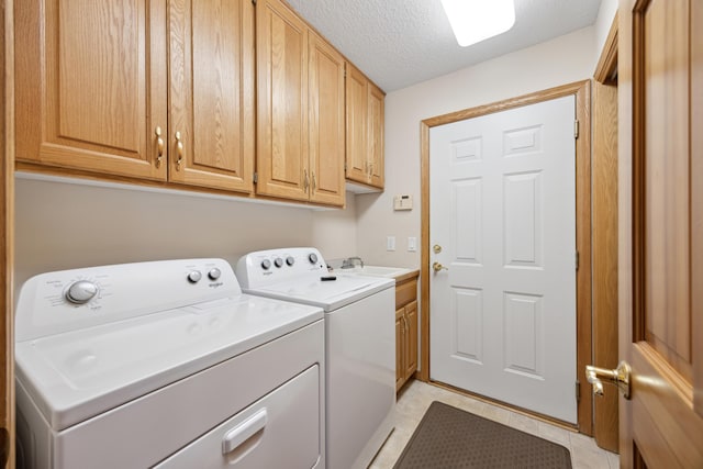 laundry area featuring washing machine and dryer, light tile patterned flooring, a textured ceiling, and cabinets