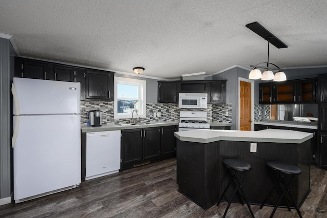 kitchen featuring a kitchen island, dark hardwood / wood-style floors, pendant lighting, sink, and white appliances