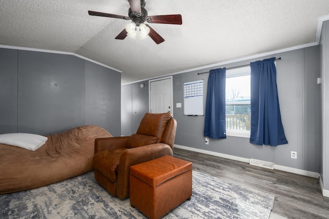 living area with lofted ceiling, hardwood / wood-style floors, ornamental molding, and a textured ceiling