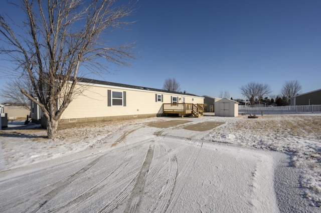 manufactured / mobile home with a wooden deck, cooling unit, and a shed