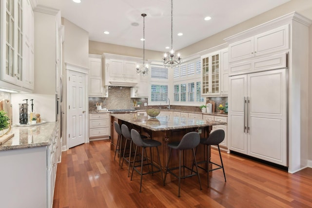 kitchen with white cabinets, a kitchen bar, light stone countertops, and a center island