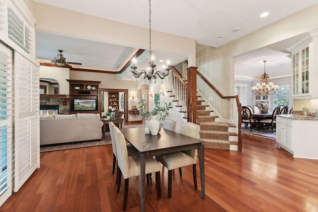 dining room with ceiling fan with notable chandelier and dark hardwood / wood-style floors