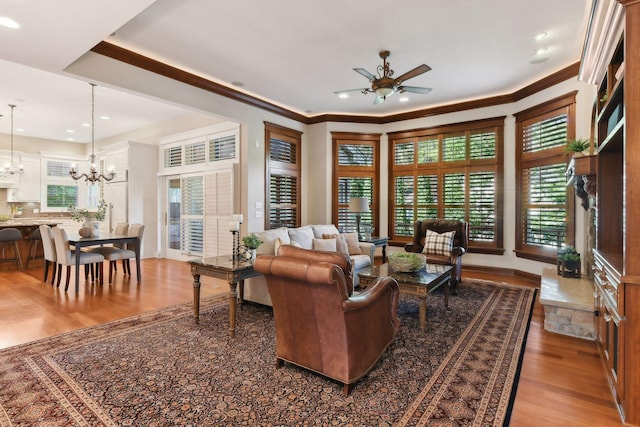 living room featuring ceiling fan with notable chandelier, ornamental molding, and hardwood / wood-style floors