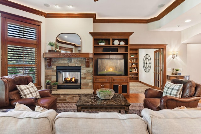 living room with a stone fireplace, ornamental molding, and hardwood / wood-style flooring