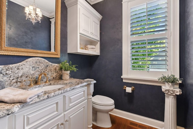 bathroom featuring toilet, hardwood / wood-style flooring, a chandelier, crown molding, and vanity