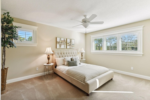 carpeted bedroom featuring ceiling fan, multiple windows, and a textured ceiling