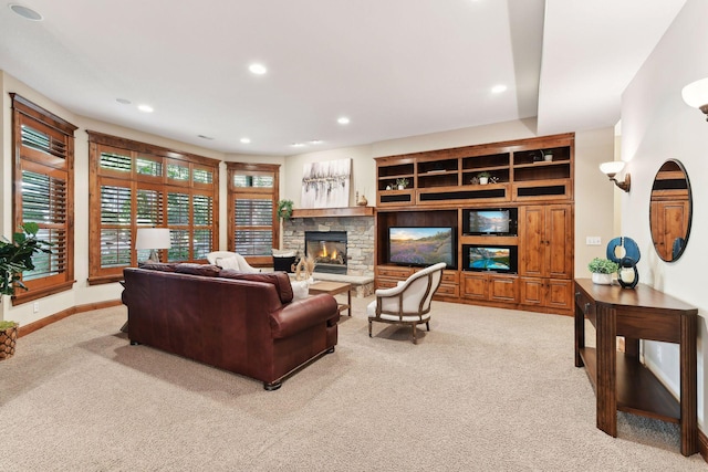 carpeted living room featuring a stone fireplace and built in shelves