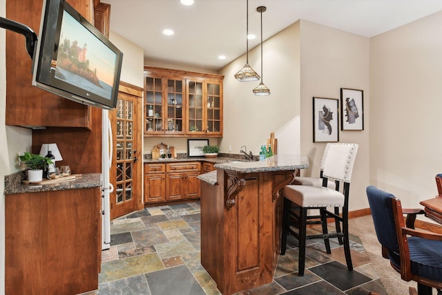 bar featuring hanging light fixtures and dark stone countertops