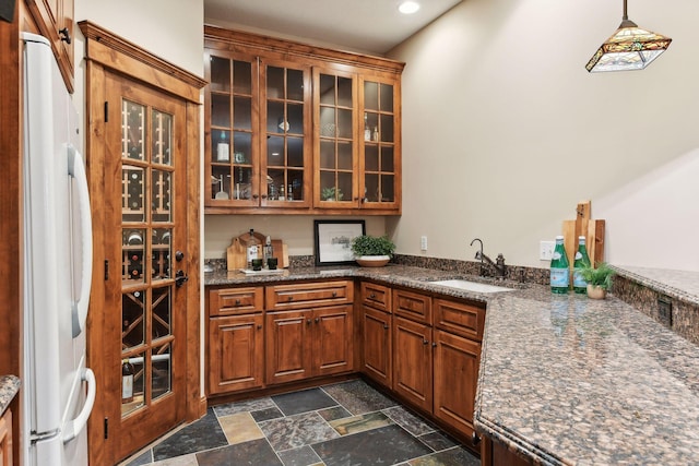 interior space featuring dark stone counters, white refrigerator, hanging light fixtures, and sink