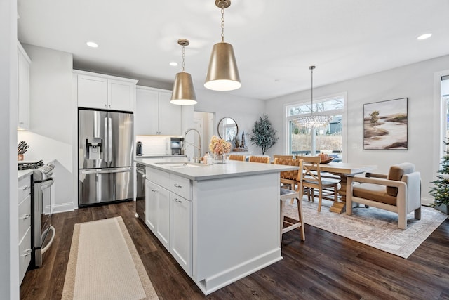 kitchen with white cabinetry, sink, stainless steel appliances, and decorative light fixtures