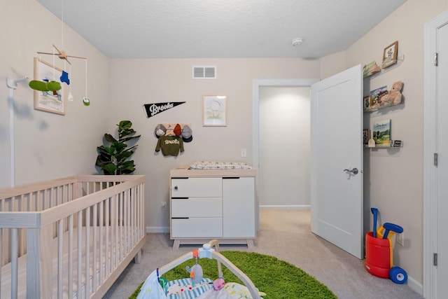 carpeted bedroom with a textured ceiling and a crib