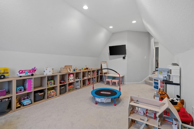 recreation room featuring a textured ceiling, carpet, and lofted ceiling