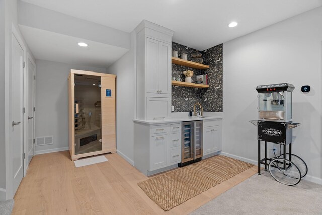 bar with white cabinetry, sink, beverage cooler, tasteful backsplash, and light hardwood / wood-style flooring