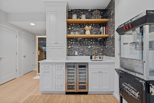 bar with white cabinetry, sink, and beverage cooler